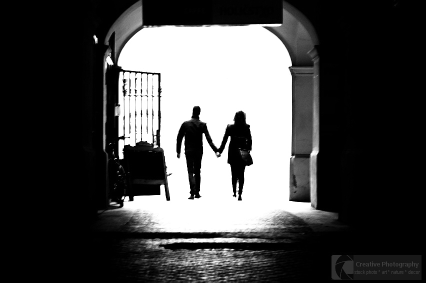 Couple hand in hand going from dark gateway to the light