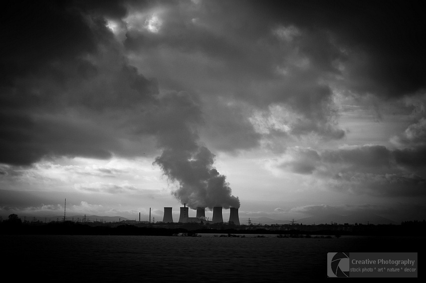 Dark smoke rises from the factory's chimney. Black and white photo